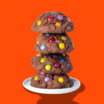 A stack of four Hunky Chunky Chocolate Gem cookies topped with colorful chocolate gems