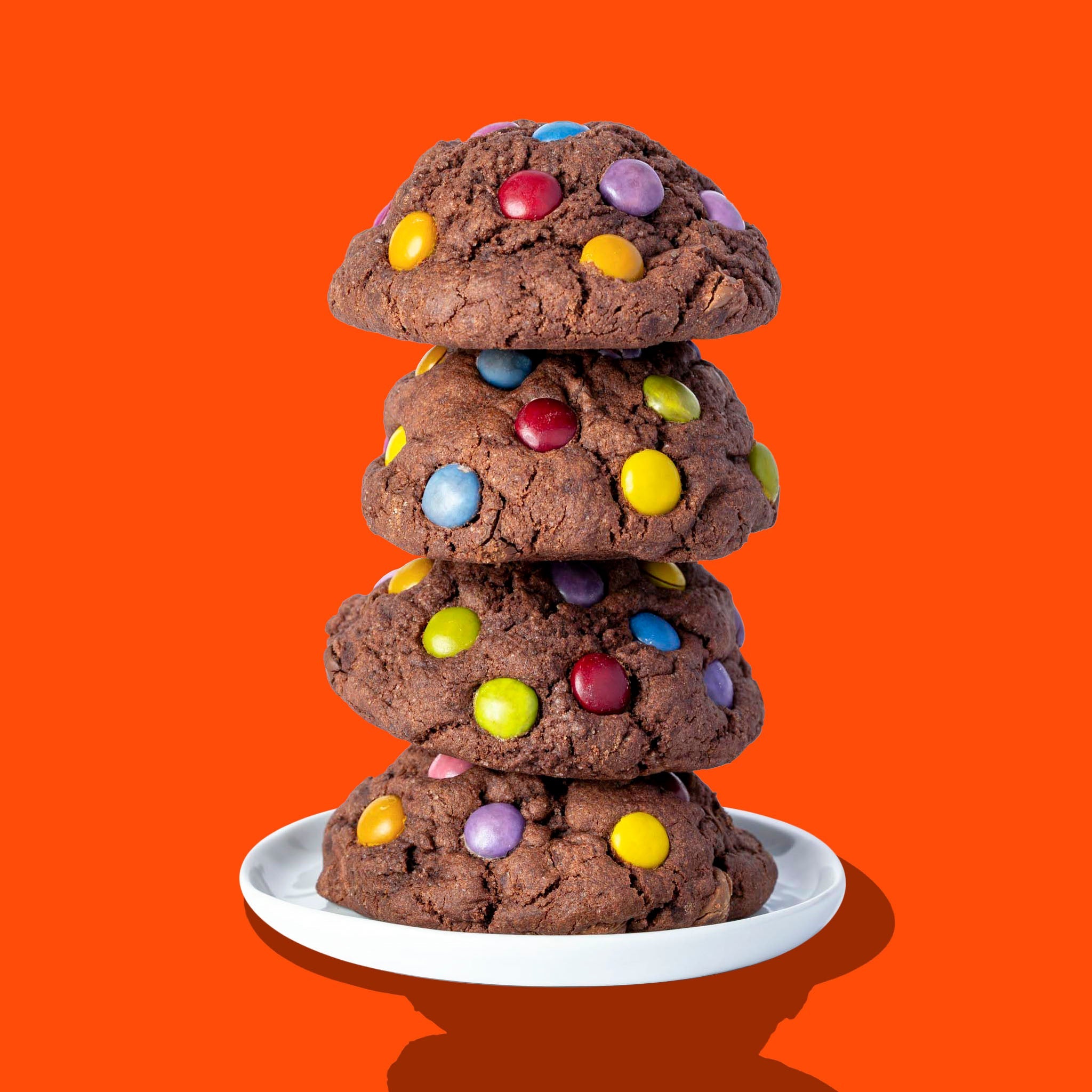 A stack of four Hunky Chunky Chocolate Gem cookies topped with colorful chocolate gems